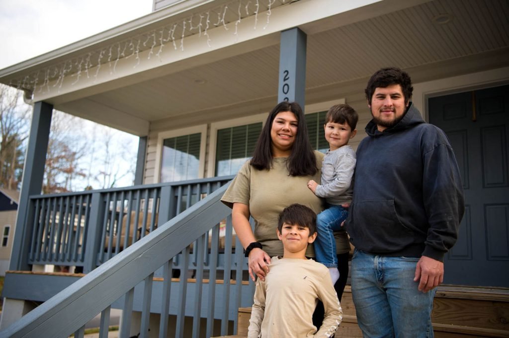 A family of four standing on the front porch of their home
