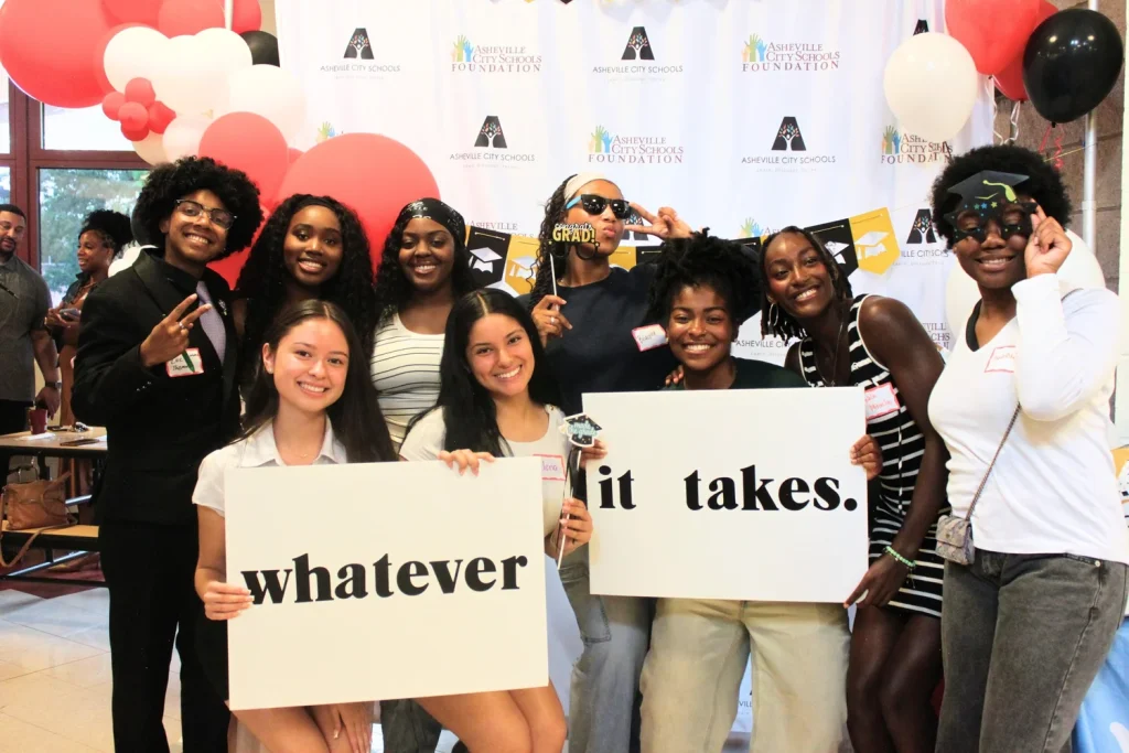 Students holding signs reading “whatever it takes” at a foundation event