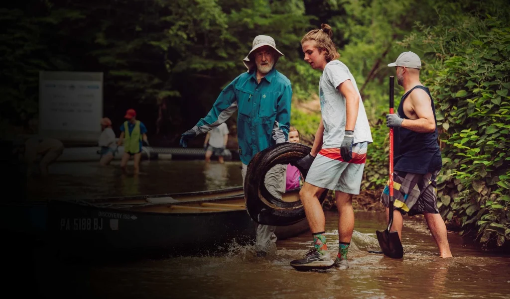 Volunteers pulling a tire and debris out of the French Broad River