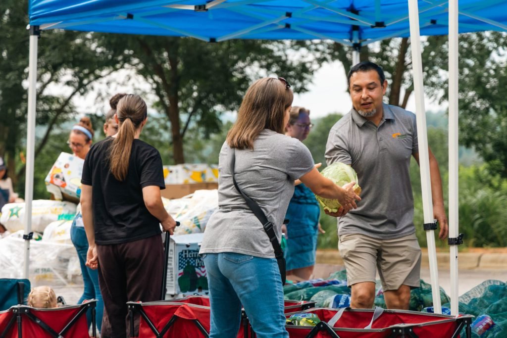 Volunteers handing out produce at an outdoor food distribution